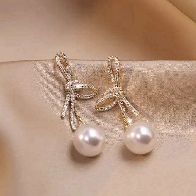 Gold pearl earrings with glittering bow